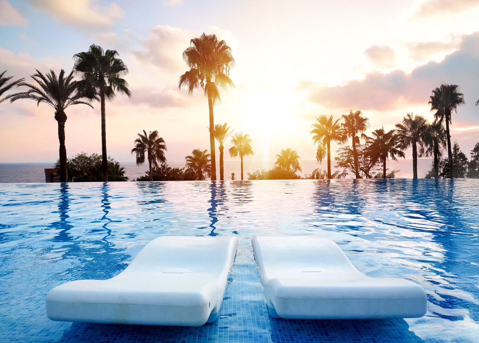Sunset over infinity pool with palm trees
