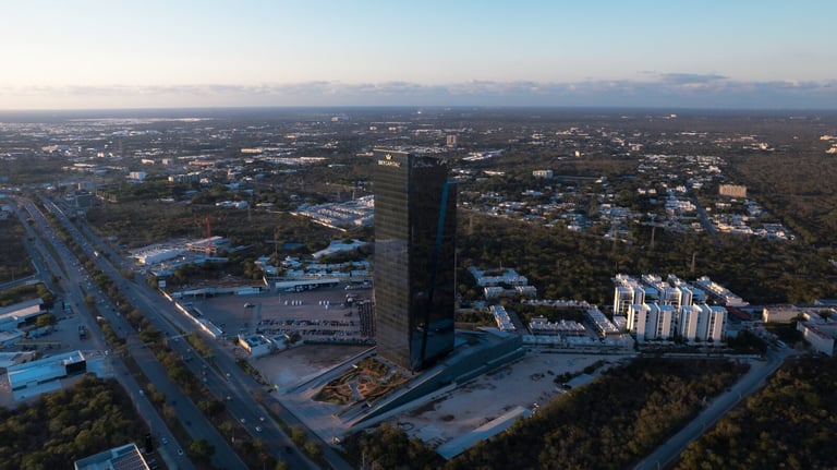 Vista aérea de The Sky, rascacielos rodeado de desarrollo suburbano y autopistas al atardecer en Mérida
