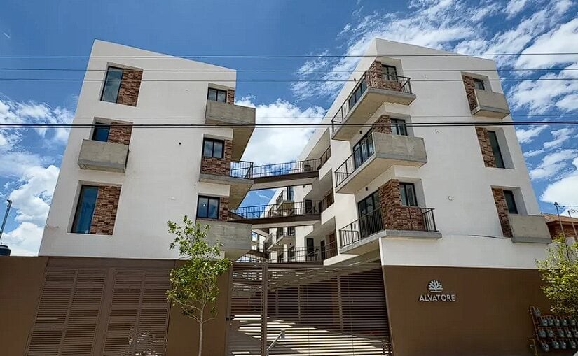 Fachada del edificio Alvatore: edificio residencial moderno con fachada blanca y acentos de ladrillo marrón, múltiples balcones y entrada con portón marrón