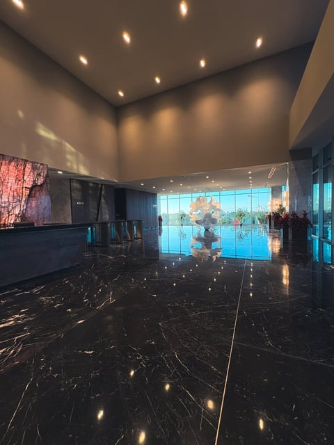 Lobby de The Sky con piso de mármol negro pulido, iluminación empotrada y pantallas digitales con vista a la ciudad