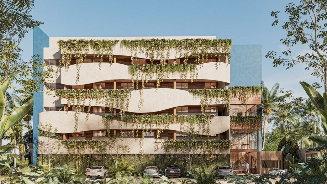Modern multi-story residential building with cascading balconies covered in lush green hanging vegetation and tropical plants surrounding the structure