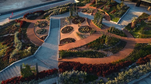 Sky Garden de The Sky con senderos curvos de cobre, jardineras circulares y caminos azules rodeados de vegetación