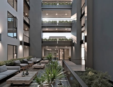 Modern courtyard with lounge seating, green plants, and multi-story building with lit windows and metal railings