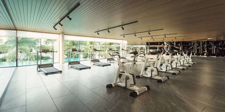 Modern gym with exercise bikes and large windows overlooking greenery