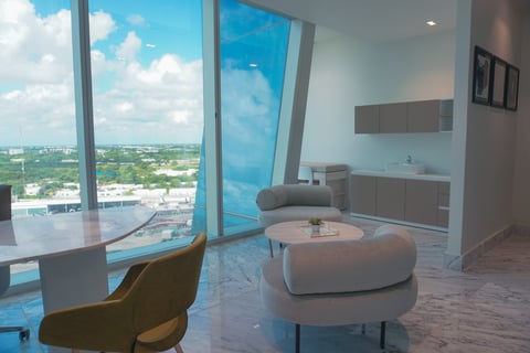 Consultorios SkyCare de The Sky con ventanales de piso a techo con vista a la ciudad y mobiliario contemporáneo