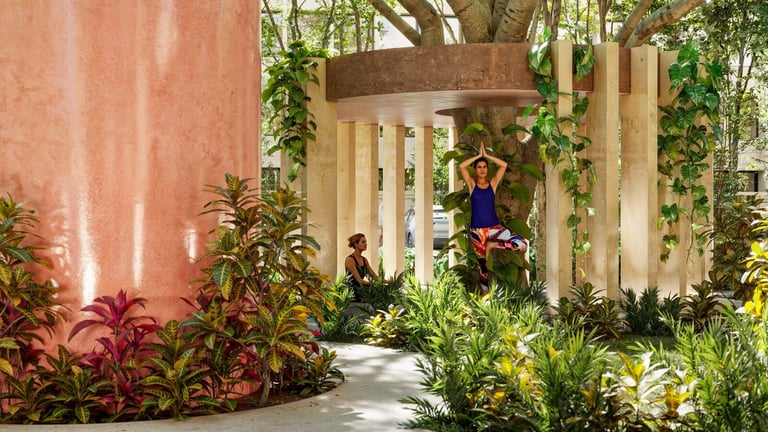 Modern garden courtyard with terracotta wall, white pergola, lush greenery, and two people walking along a stone pathway