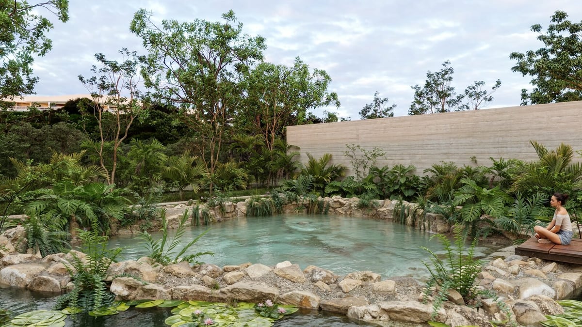 Turquoise hot spring pool surrounded by rocks and tropical vegetation with wooden structures in background