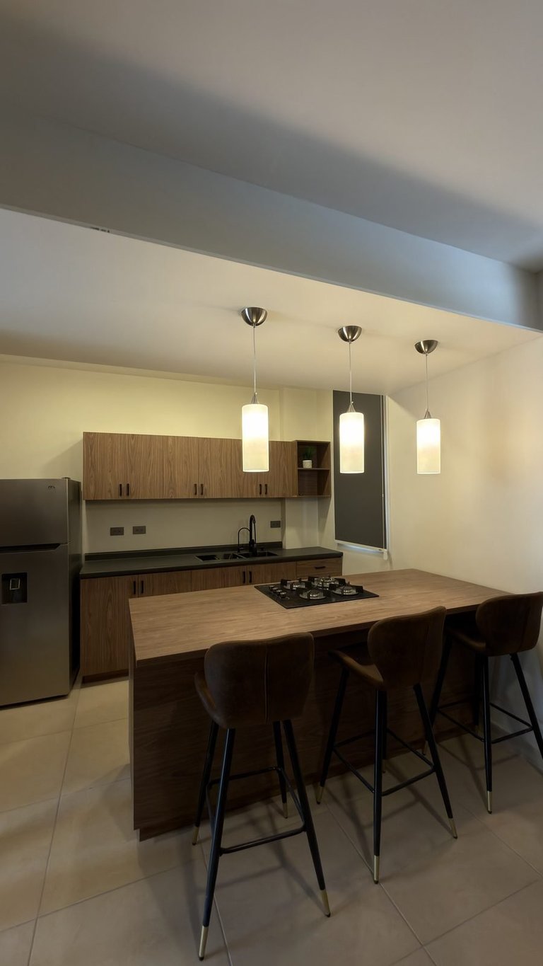Modern kitchen with wooden island, bar seating, gas cooktop, pendant lights, and wood cabinetry
