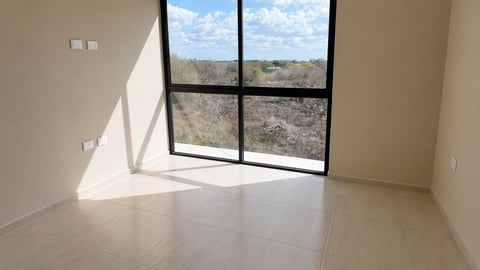 Empty modern room with large black-framed window overlooking rocky landscape and sky