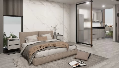 Recámara con cama tapizada beige, muro de mármol y puertas de vidrio con marco negro hacia el baño