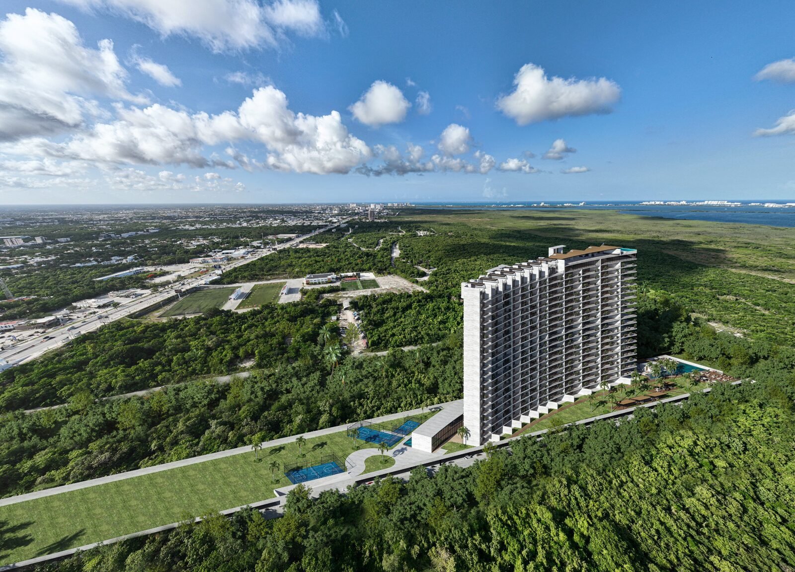 Aerial view of a modern high-rise residential building surrounded by lush green landscape and forest with a highway in the distance