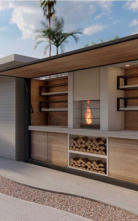 Área de asador exterior de Casa José Matías con cocina techada, acabados en madera, chimenea y almacén para leña