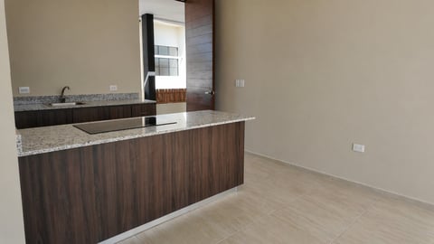 Modern kitchen with dark wood cabinetry, granite countertop, stainless steel sink, and neutral beige walls with light tile flooring